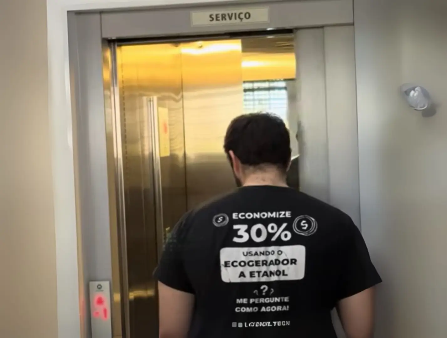 Homem usando camisa Liconic entra em elevador de serviço com economia garantida via ecogerador.
